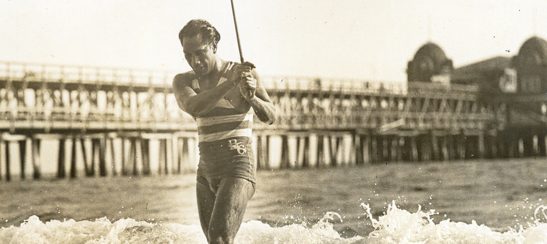 Duke exiting the water with stick in his hand in front of pier