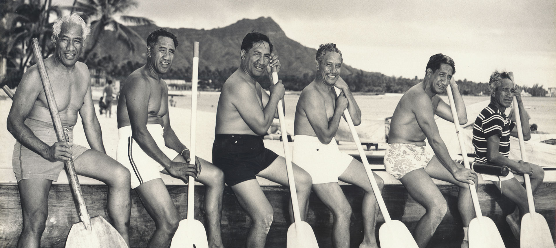 Duke and men sitting on dock with oars