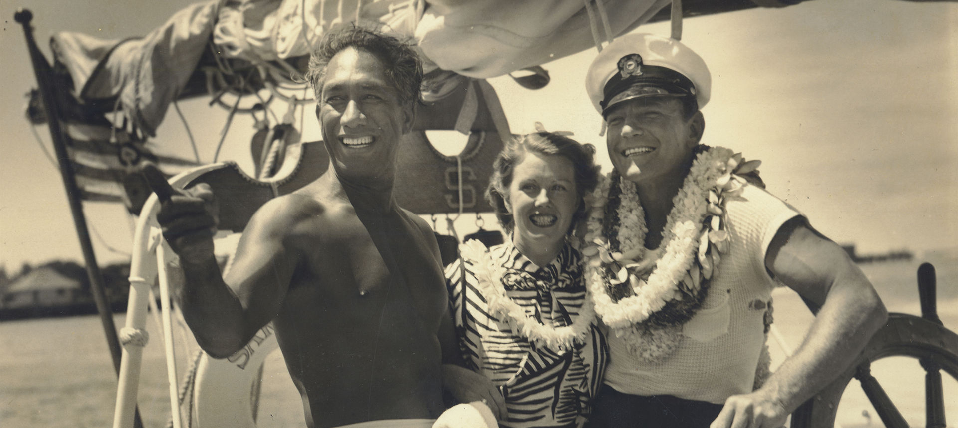 Duke on a boat pointing something out to a sailor couple