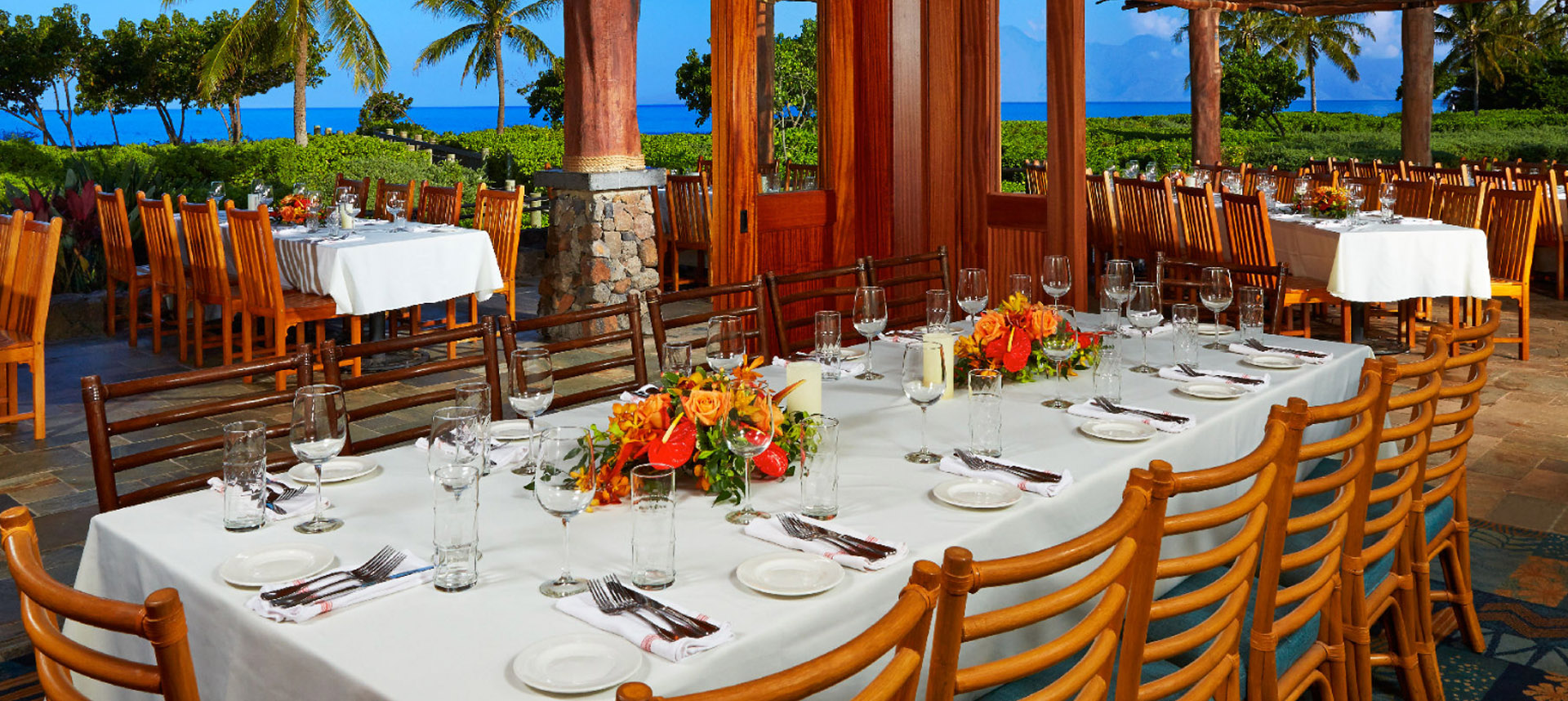 Three large dining tables set with and ocean view