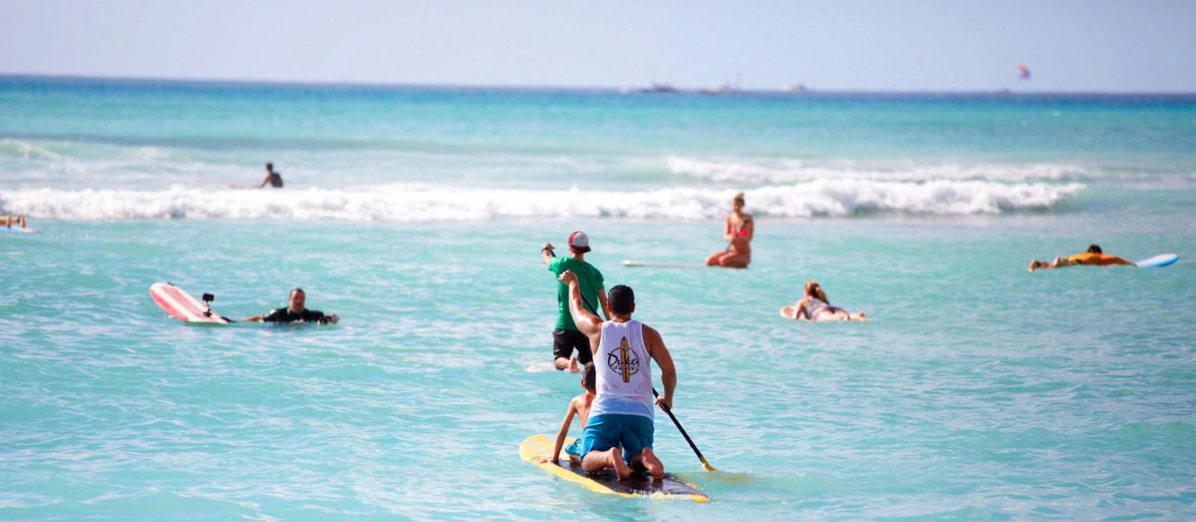 People in the ocean surfing and paddle boarding