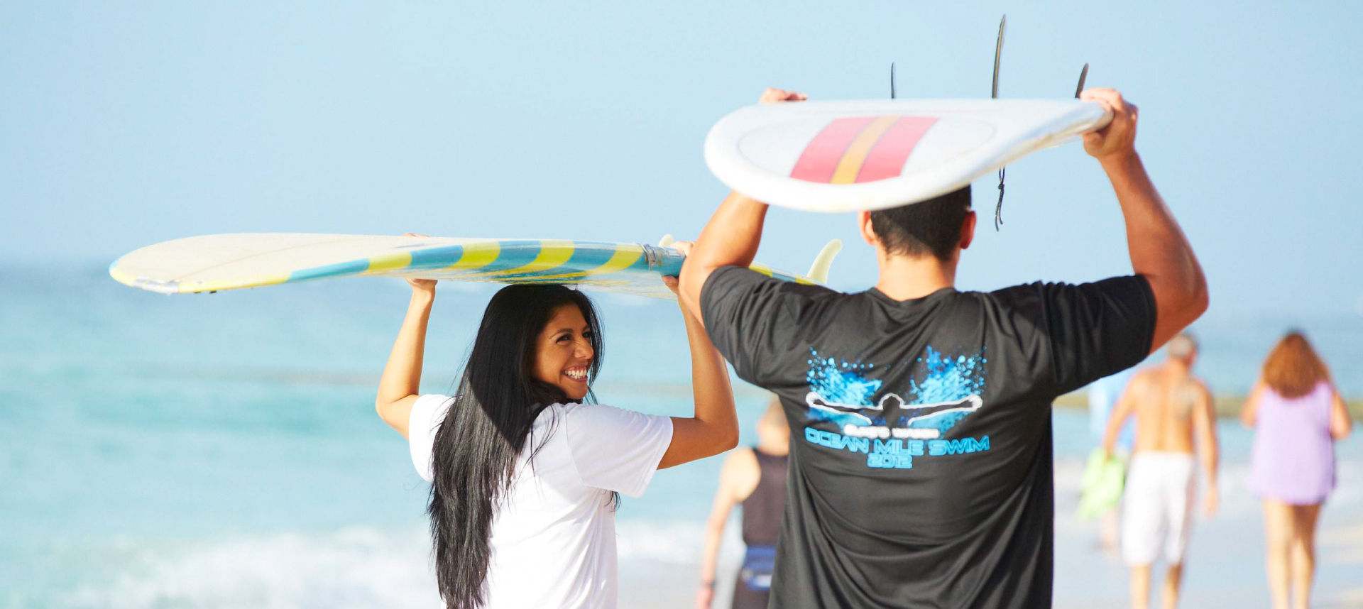 Male and female holding surfboards above their heads at the beach