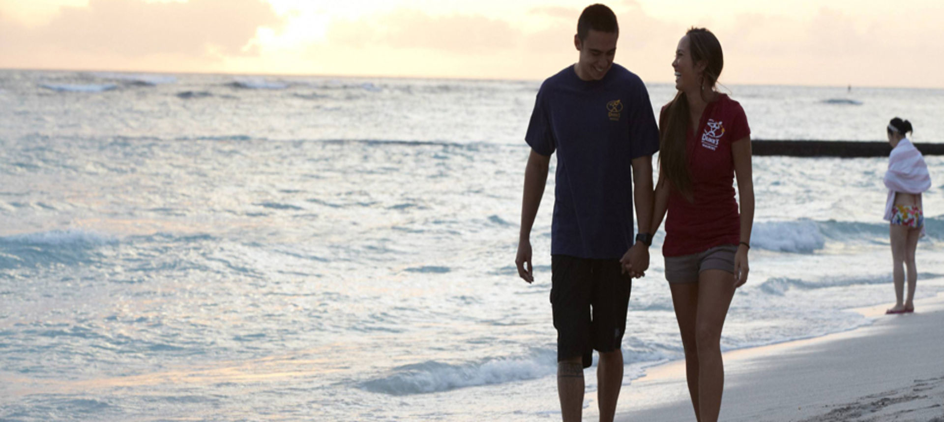 Male and female holding hands while walking along the shoreline