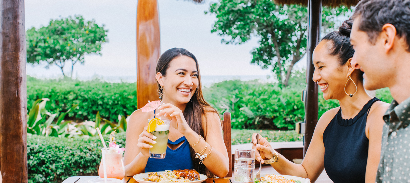 Two women and one man eating dinner by the beach