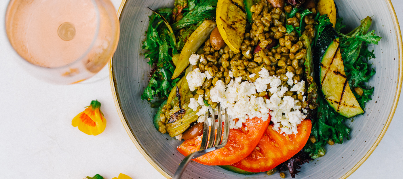 Salad with grilled vegetables and tomato with a glass of bubbly